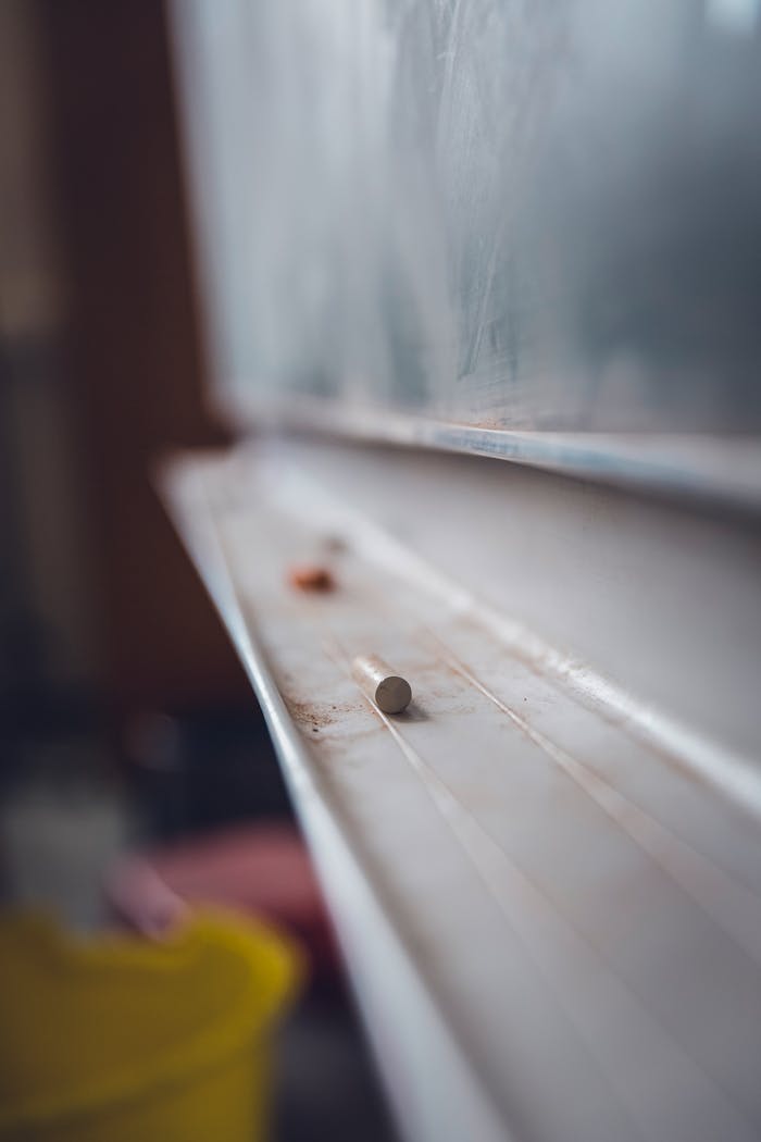 Dusty chalk resting on chalkboard ledge creating educational atmosphere.